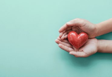 hands holding red heart on blue background, health care, love, organ donation, family insurance and CSR concept, world heart day, world health day